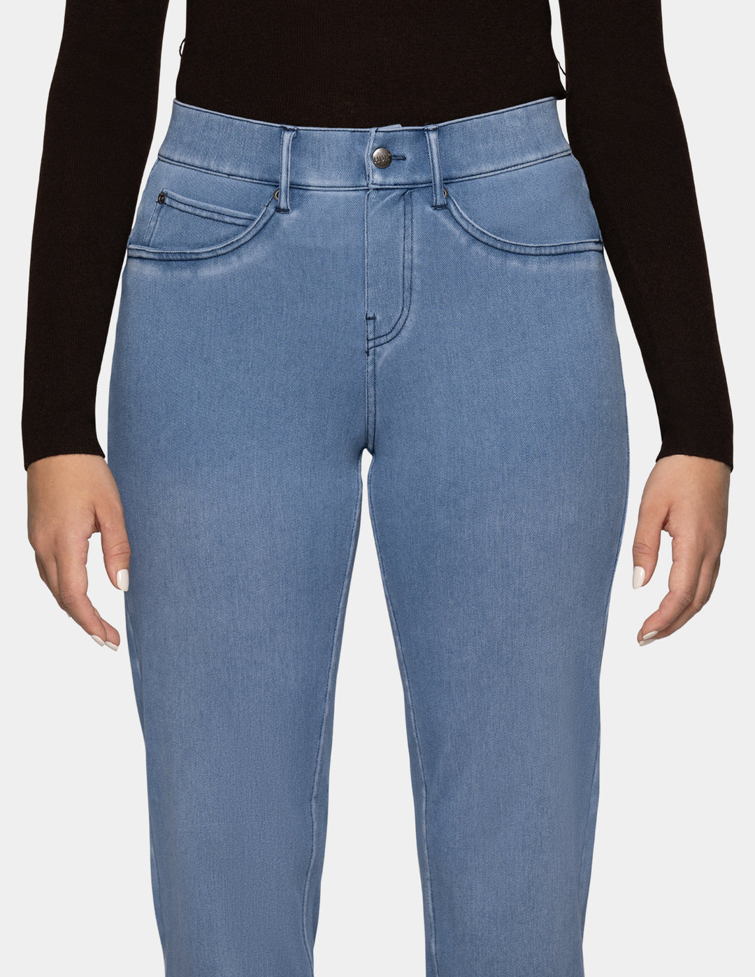 A detailed view of a model wearing light blue denim pants, and a long sleeve black top photographed against a light gray background.