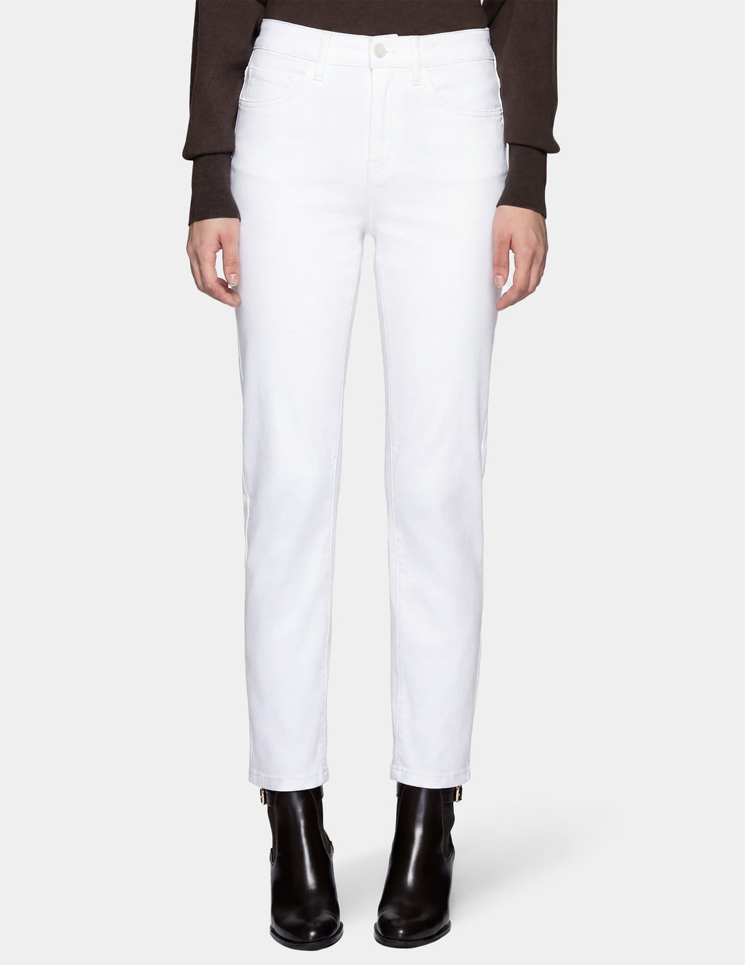 A model wearing white pants, a long sleeve top, and black boots photographed against a light gray background.