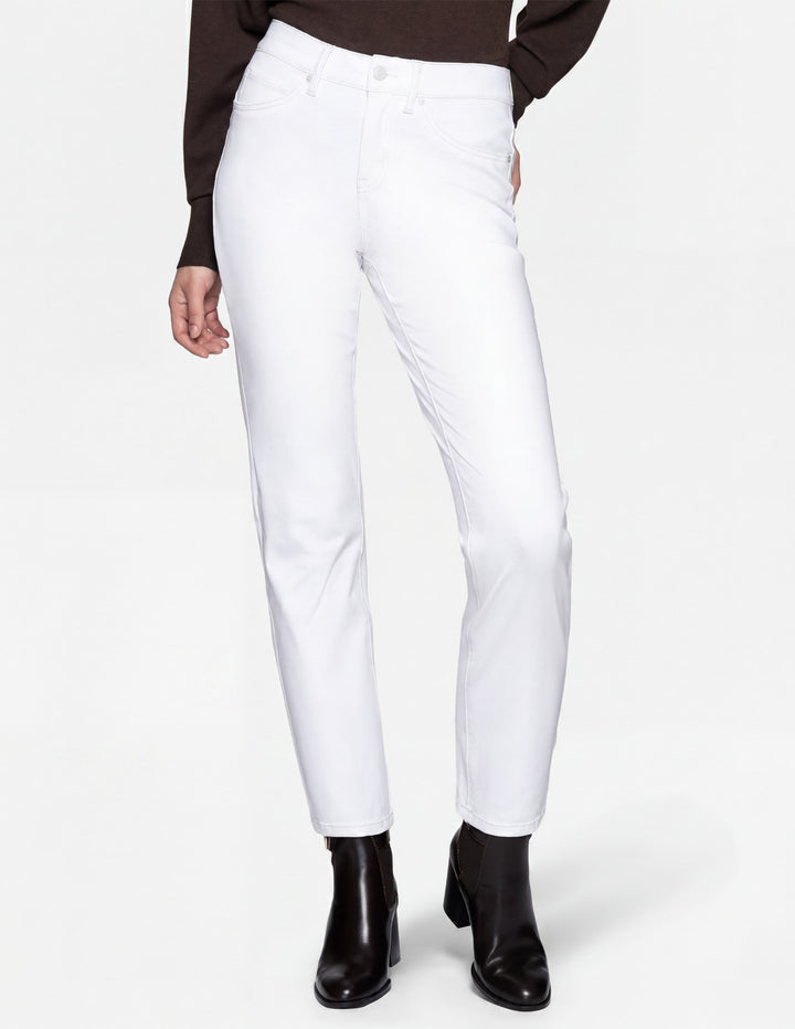 A model wearing white pants, a long sleeve top, and black boots photographed against a light gray background.
