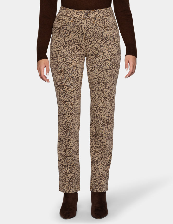 A model wearing cheetah pants, a long sleeve brown top, and brown boots photographed against a light gray background.