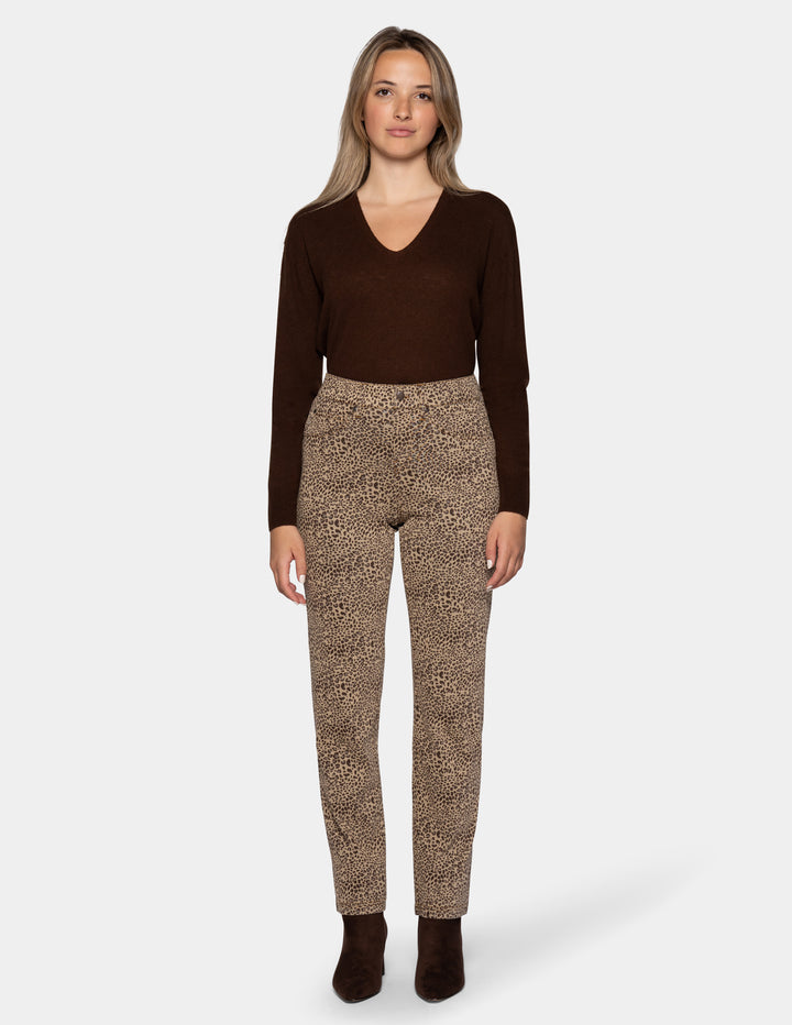 A model wearing cheetah pants, a long sleeve brown top, and brown boots photographed against a light gray background.