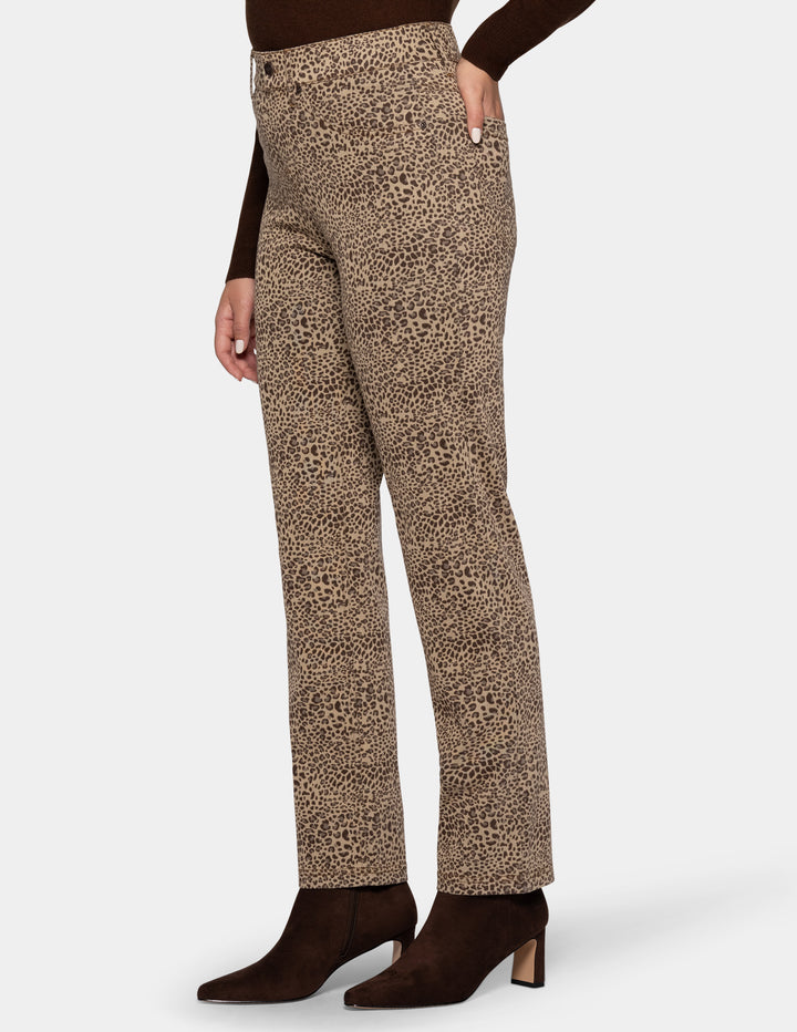 A model wearing cheetah pants, a long sleeve brown top, and brown boots photographed against a light gray background.