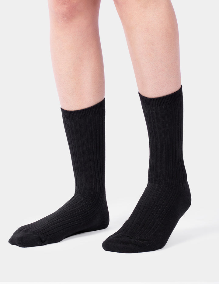 A model wearing a pair of black crew socks photographed against a light gray background.
