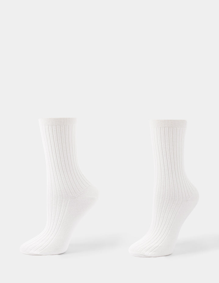 An ivory pair of ribbed crew socks displayed against a light gray background.