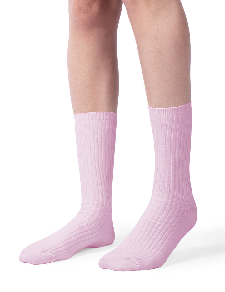 A model wearing a pair of pink crew socks photographed against a light gray background.
