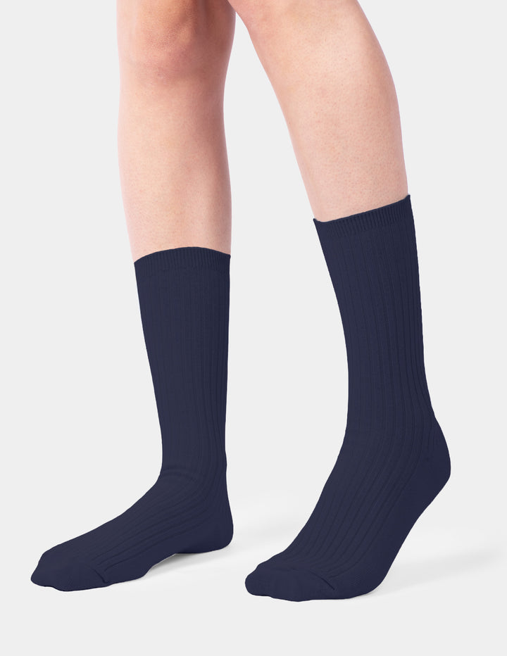 A model wearing navy crew socks photographed against a light gray background.