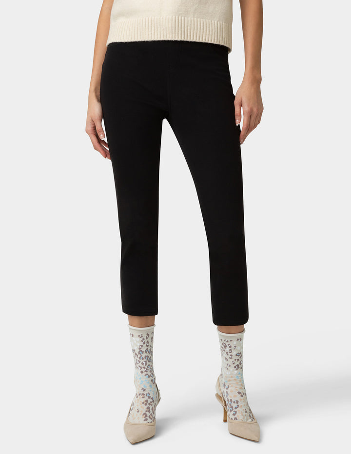 Person wearing black pants and light-colored socks on a white background