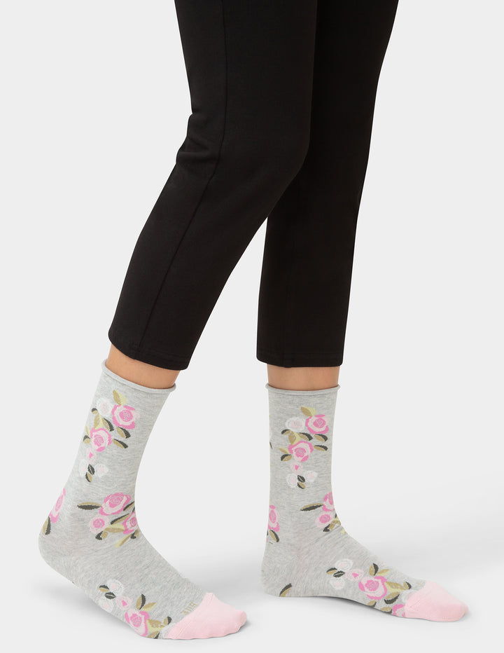 Gray socks with floral patterns worn with black leggings on a white background