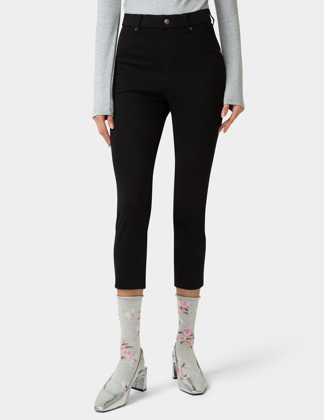 Person wearing black pants with a plain background