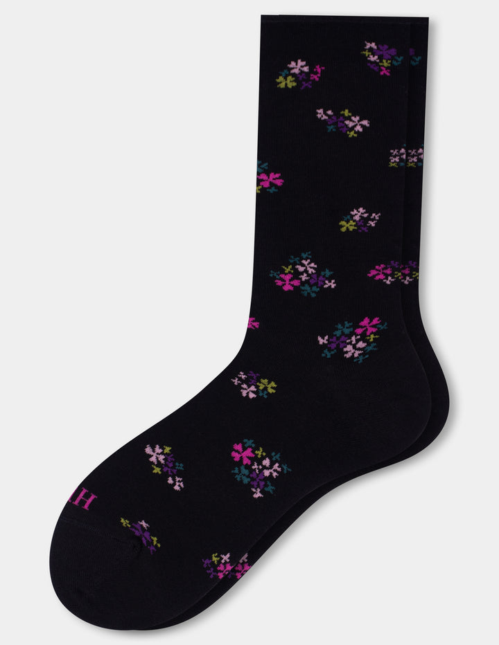 A single black crew sock with a scattered small floral print in pink, purple, and green shown on a light gray background.