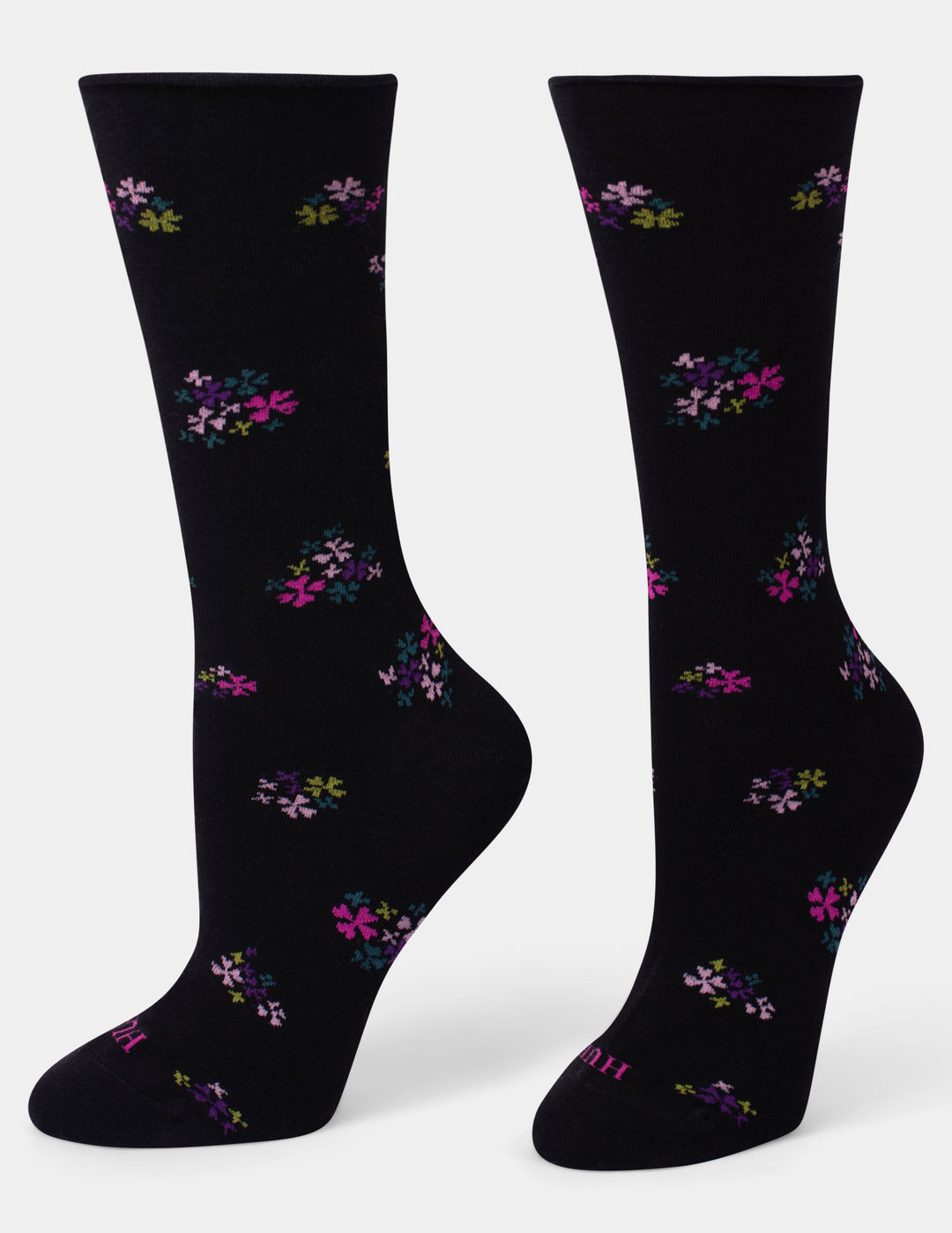 A pair of black crew socks with a scattered floral pattern in pink, purple, and green, displayed against a light gray background.