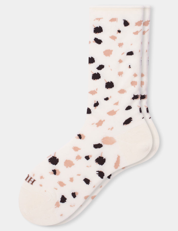 A pair of ivory crew socks with a scattered animal print pattern of black and pink spots, shown against a light gray background.