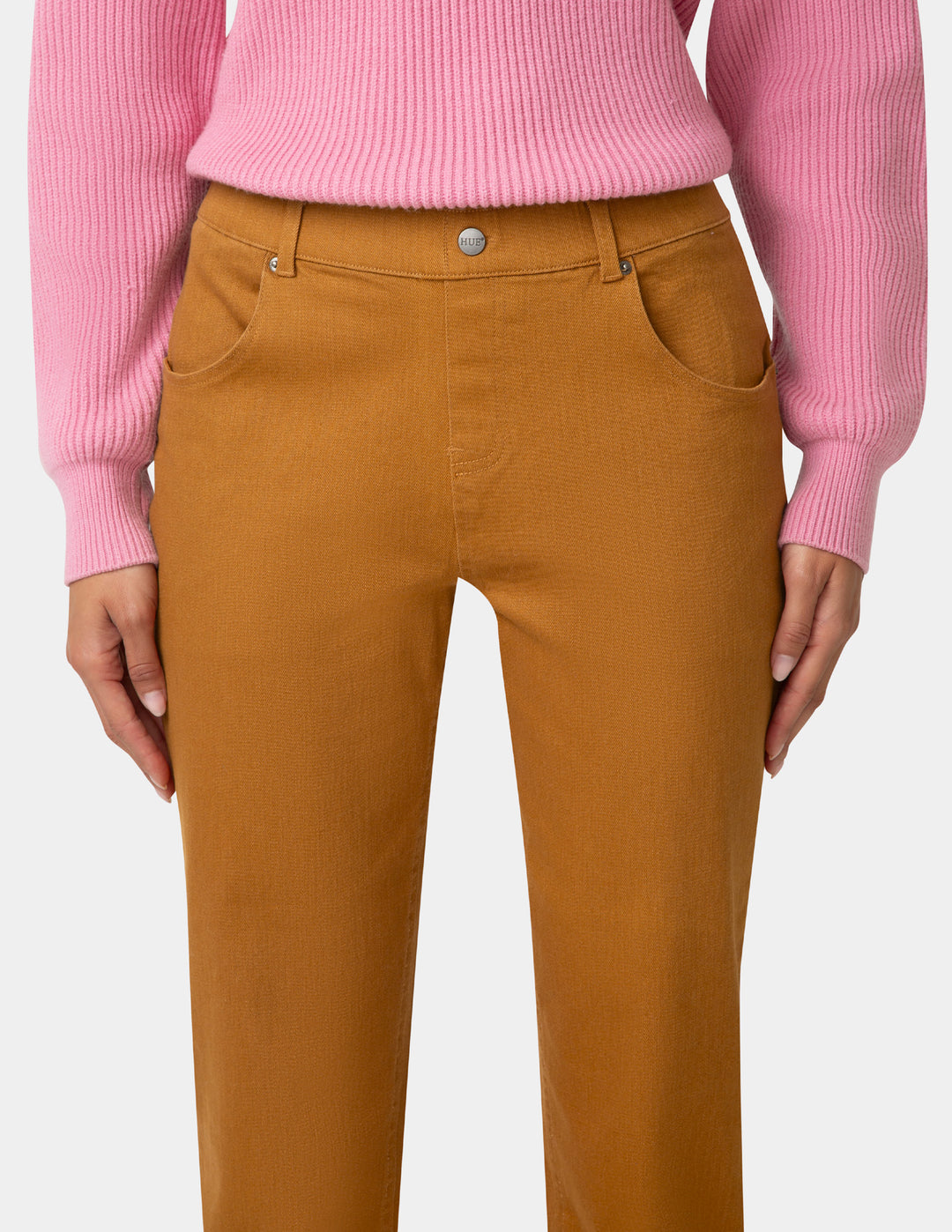 Brown pants worn with a pink sweater on a white background