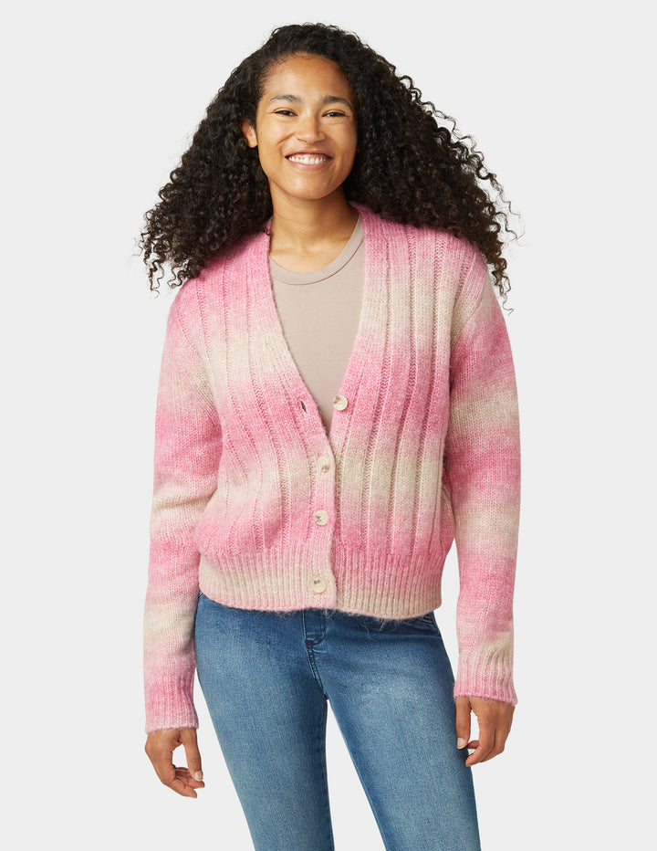 Pink and white sweater with blue jeans on a plain background