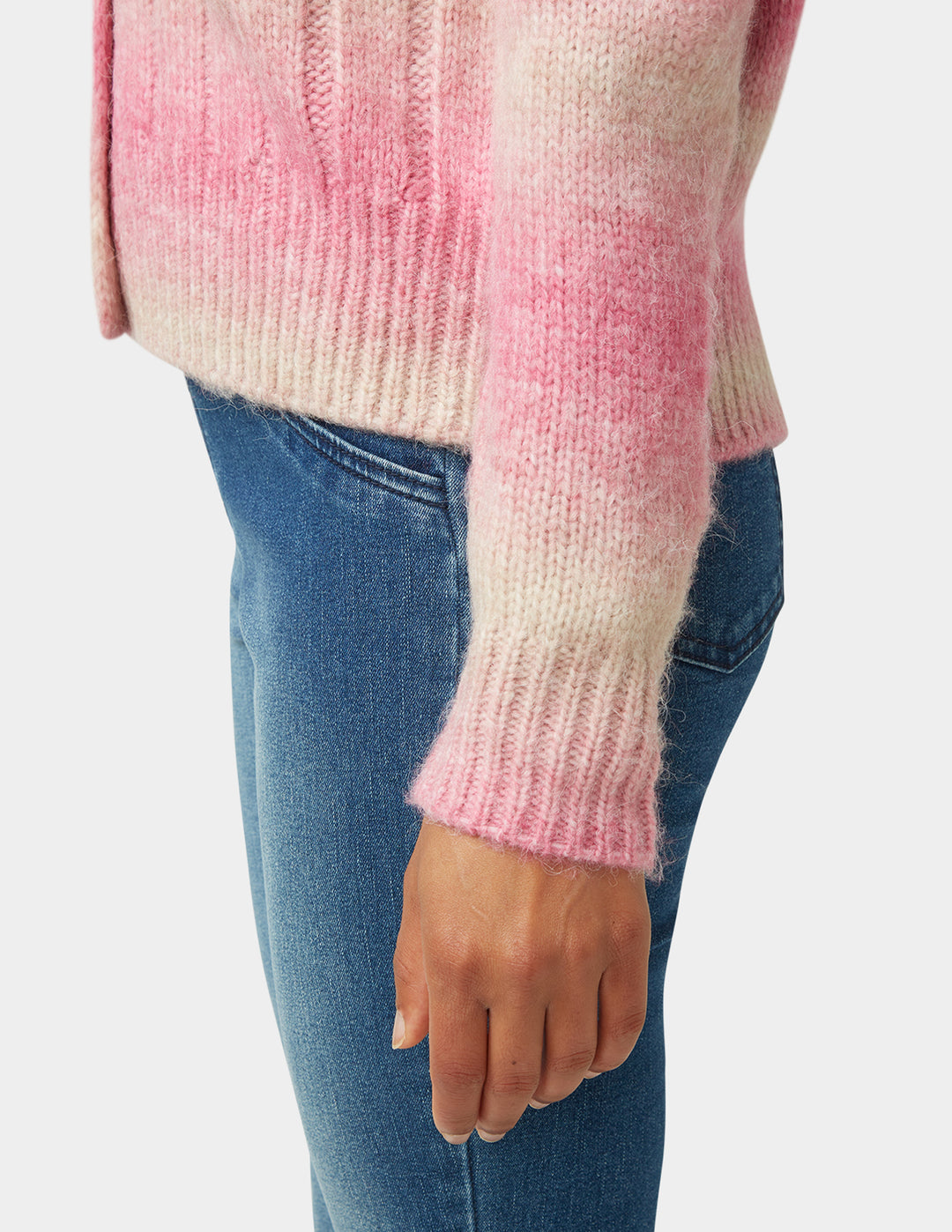 Pink and white sweater with blue jeans on a plain background