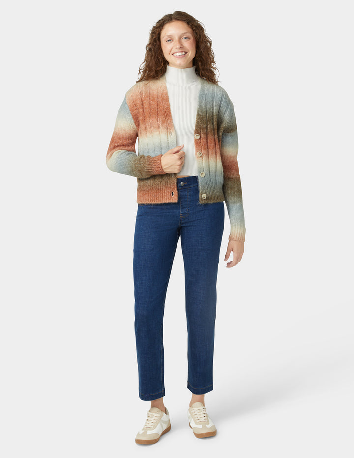 Woman wearing a colorful striped sweater and blue jeans on a white background