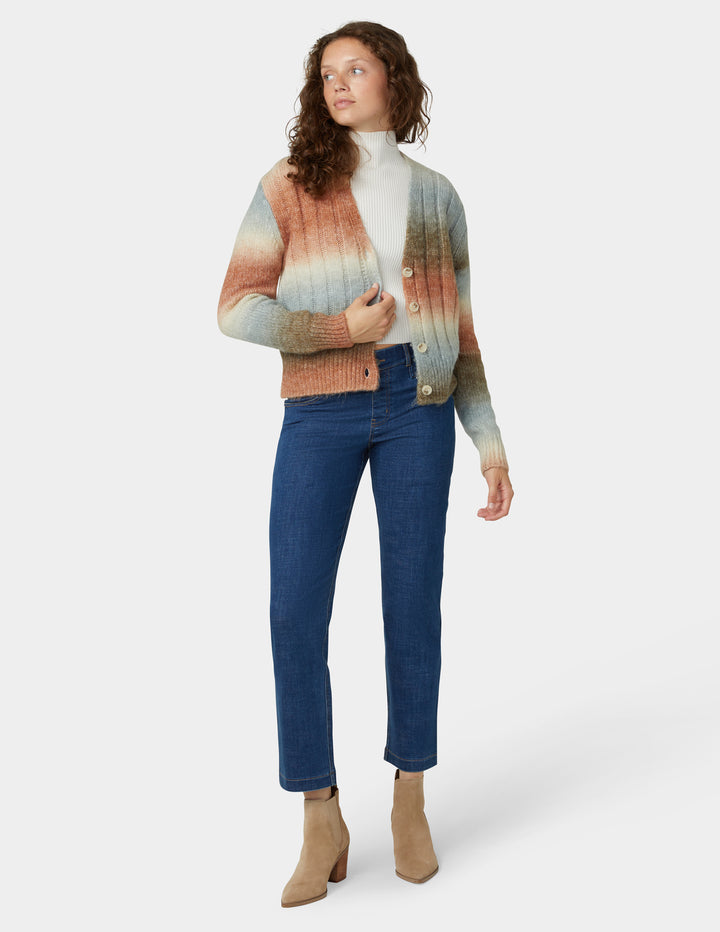 Woman wearing a colorful striped sweater and blue jeans on a white background