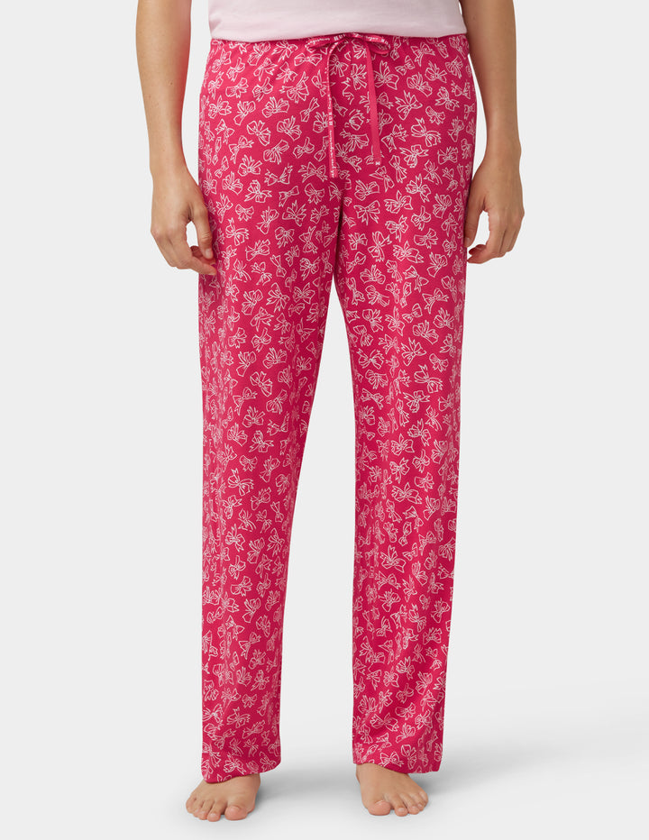 Person wearing pink bow design pajama pants on a white background