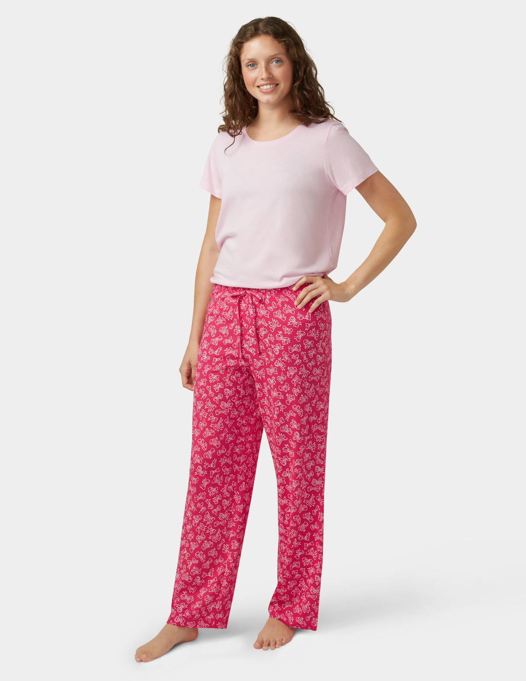 Woman wearing a pink t-shirt and red patterned pants on a white background