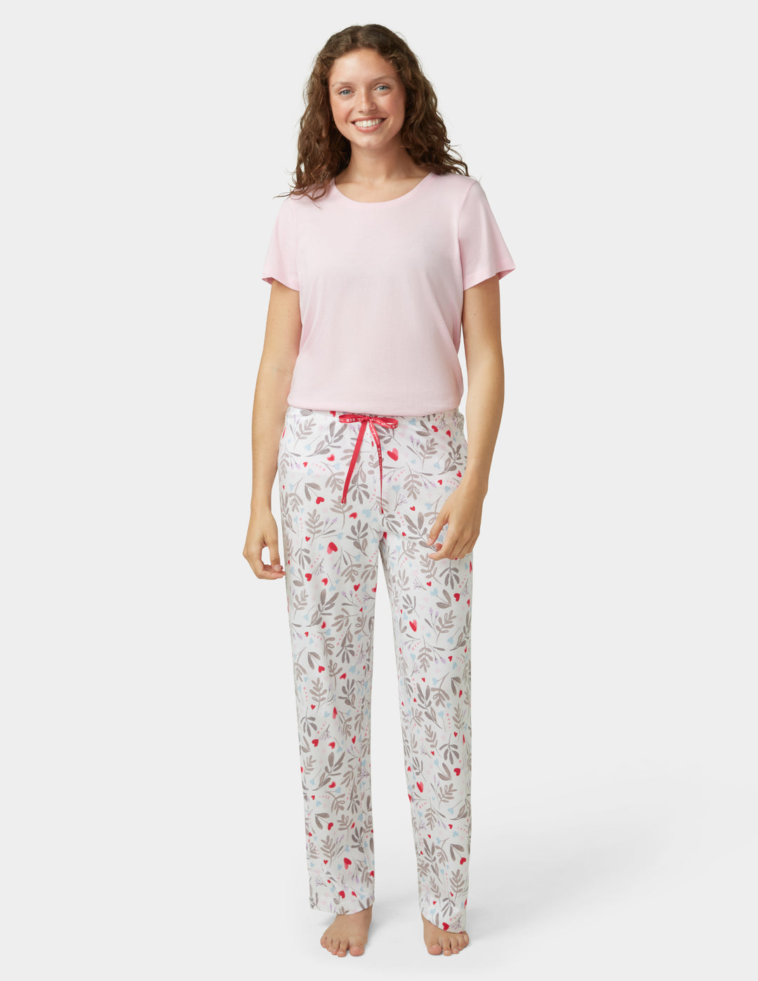 Woman wearing a pink top and patterned pants on a white background