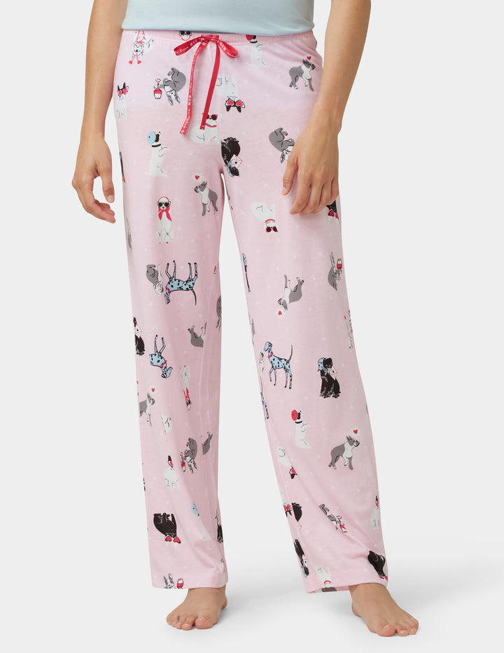 Pink pajama pants with dog pattern worn by a person on a white background