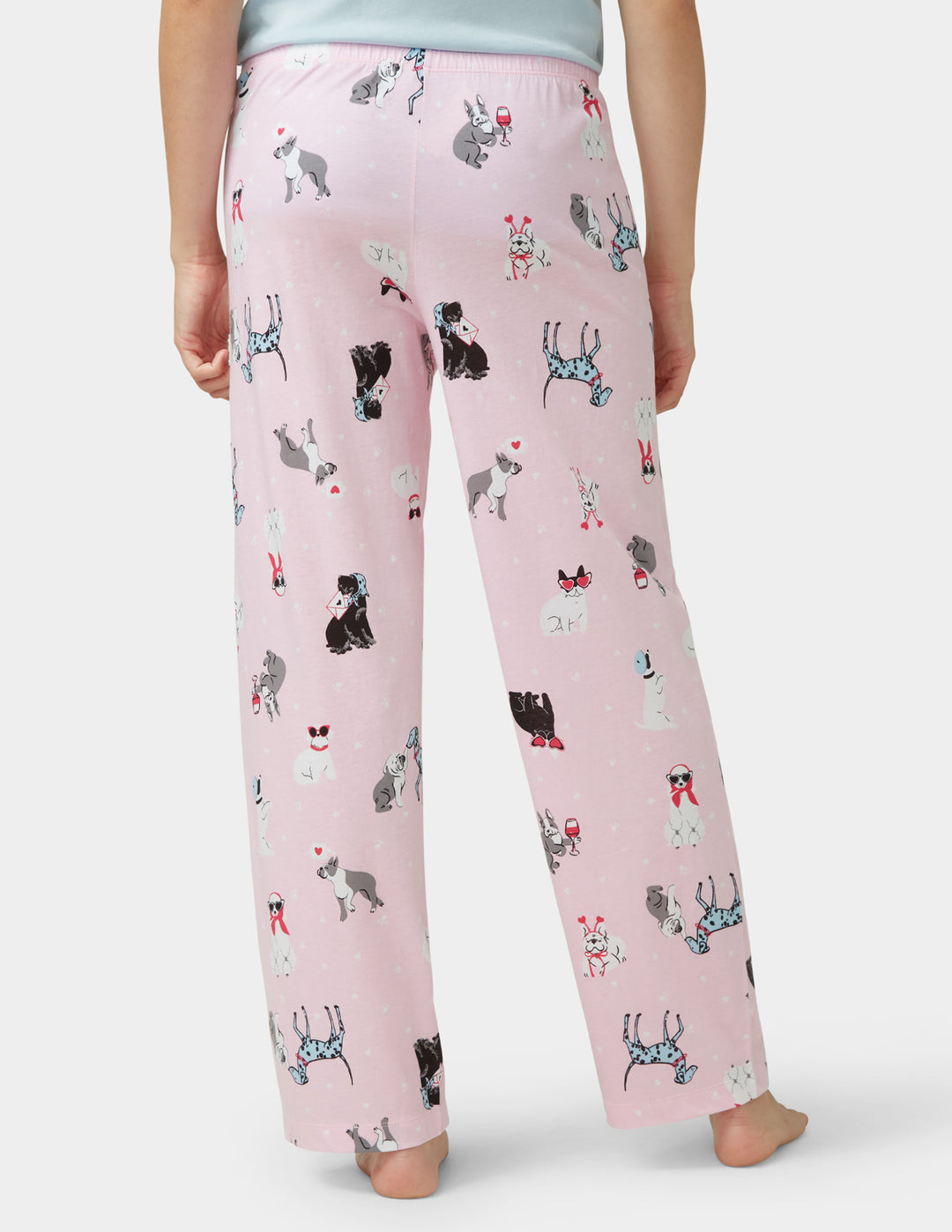 Pink pajama pants with dog pattern worn by a person on a white background