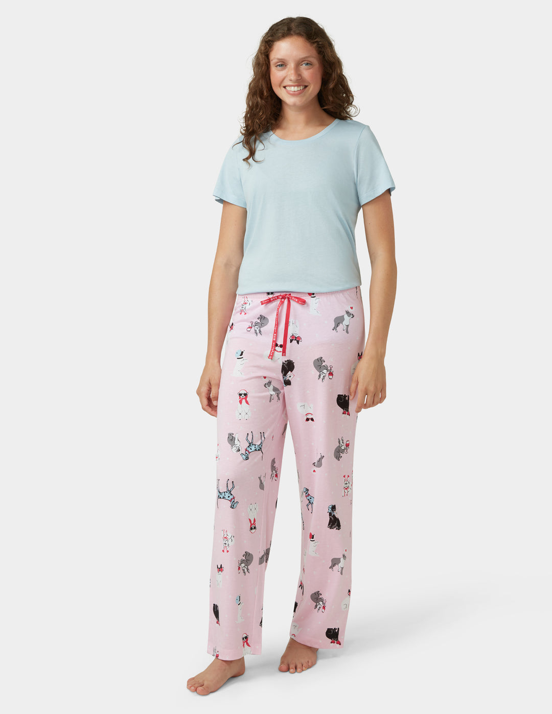 Woman wearing a light blue t-shirt and pink pajama pants with animal prints on a white background