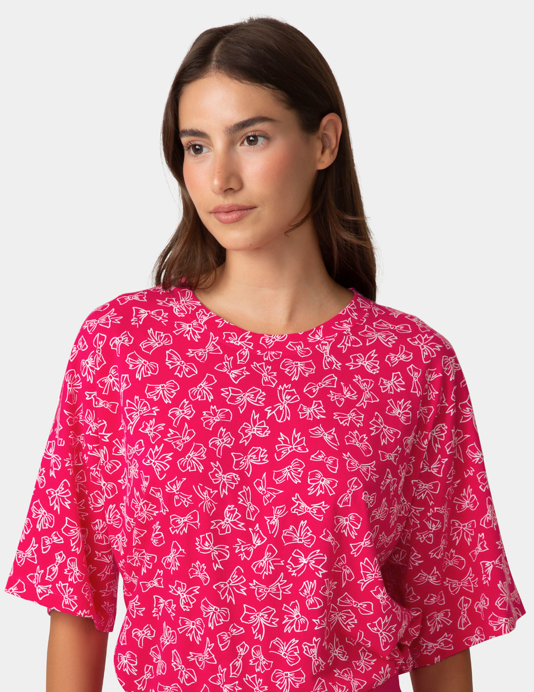 Woman wearing a pink shirt with white patterns on a white background
