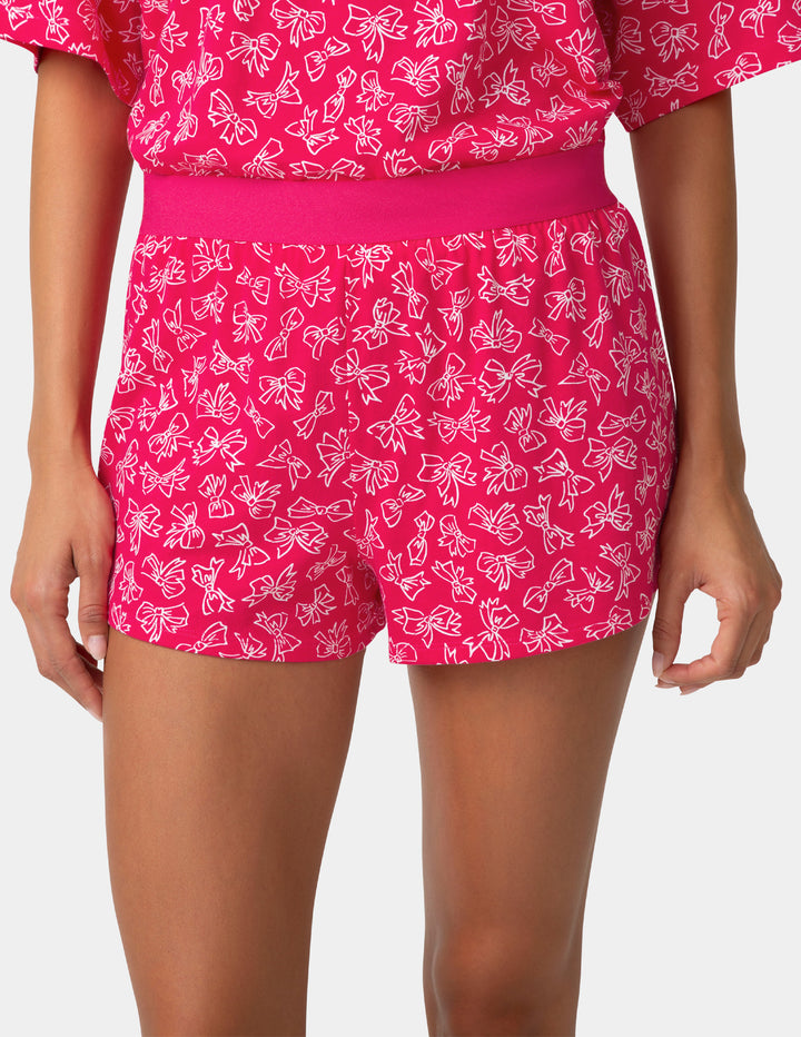 Person wearing pink shorts with white bow pattern on a plain background