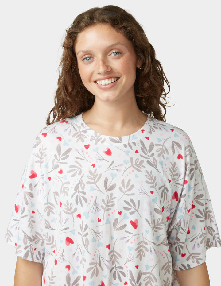 Woman wearing a white pajama shirt with heart details on a white background