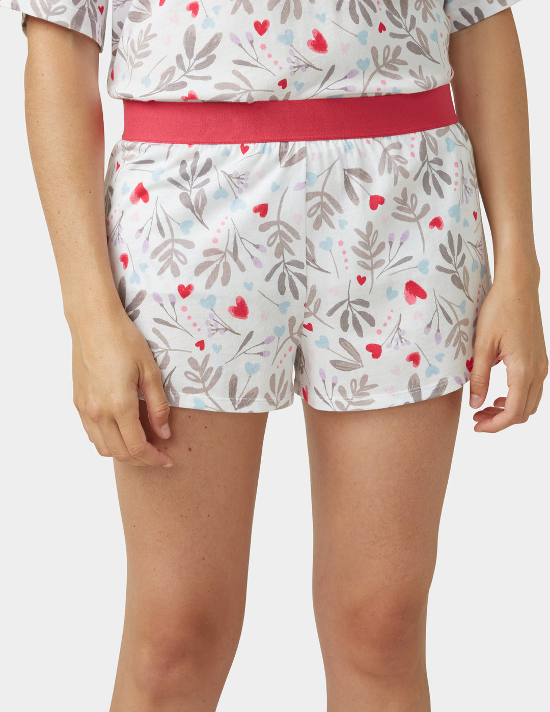 Woman wearing a white pajama shorts with heart details on a white background