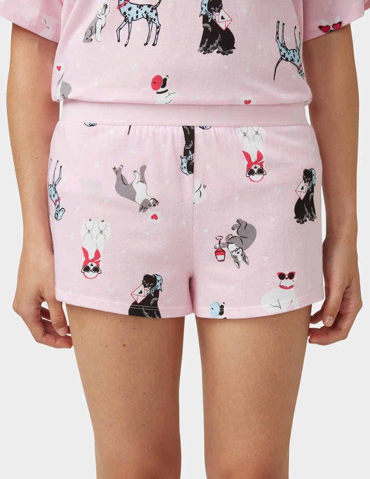 Person wearing light pink pajama shorts on a white background