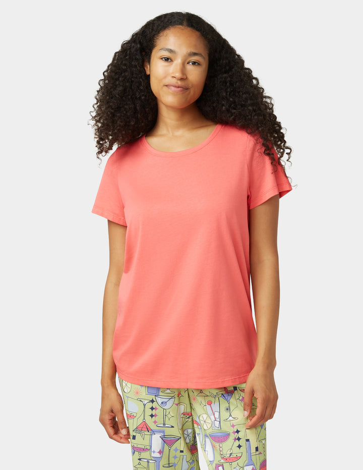Woman wearing a coral t-shirt and colorful pants on a white background