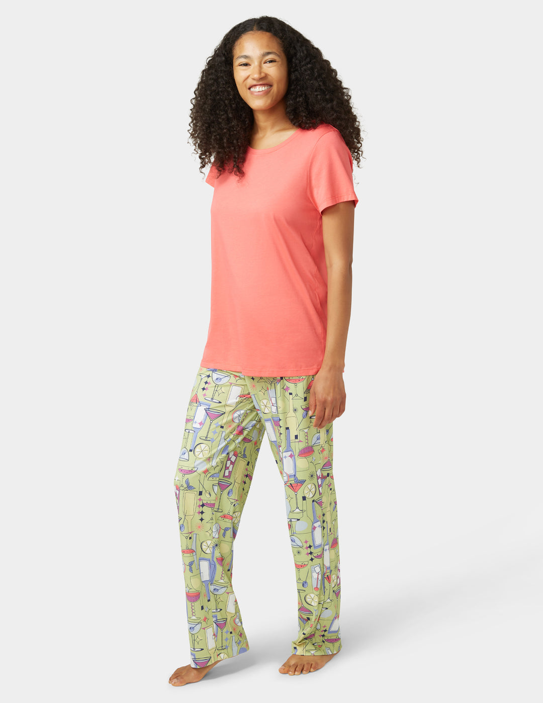 Woman wearing a coral top and green patterned pants on a white background