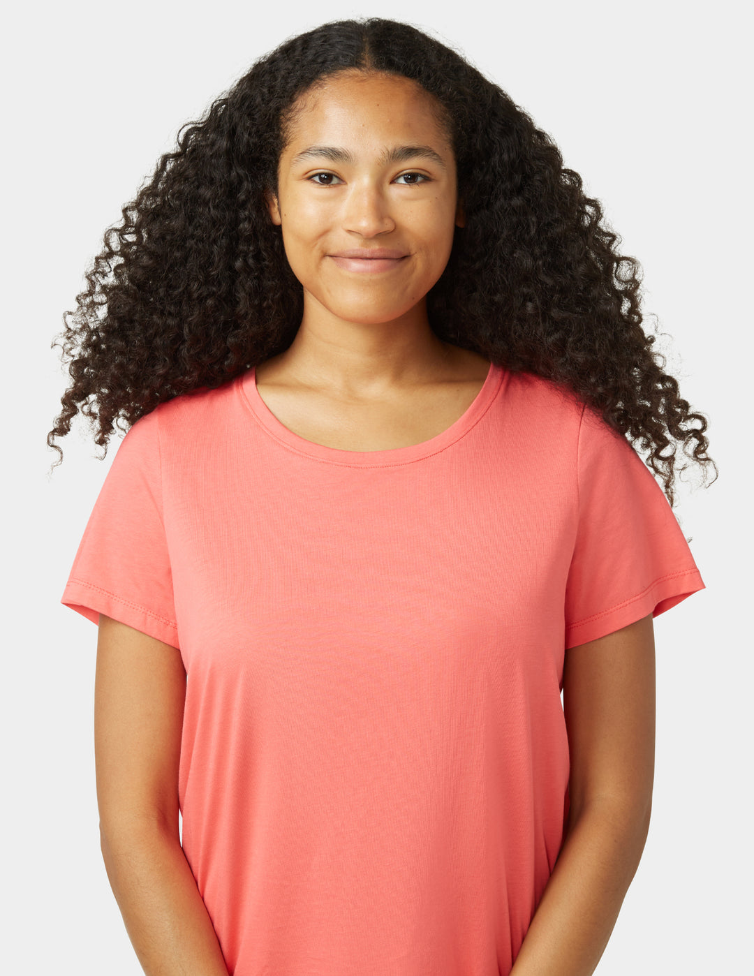 Person wearing a coral t-shirt against a plain background