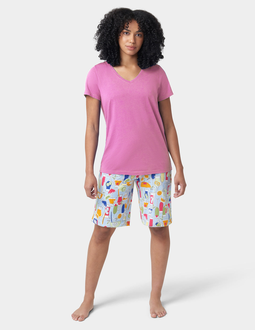 Woman wearing a pink shirt and colorful shorts on a white background