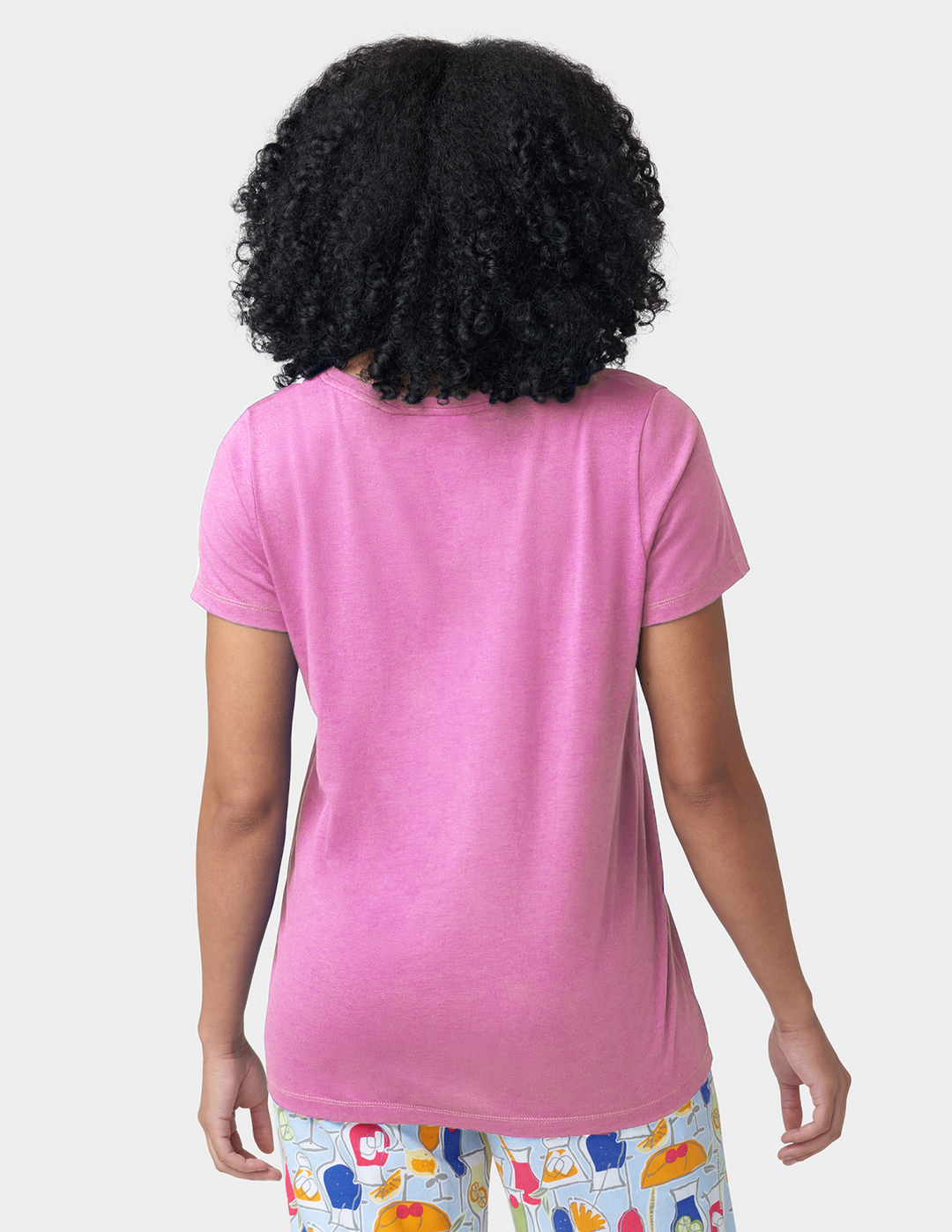 Person wearing a pink t-shirt with colorful pajama pants on a white background