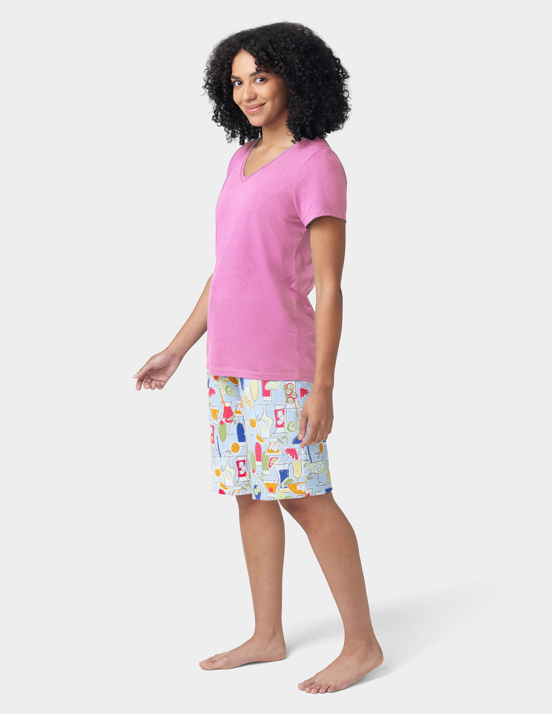 Woman wearing a pink top and patterned shorts on a white background