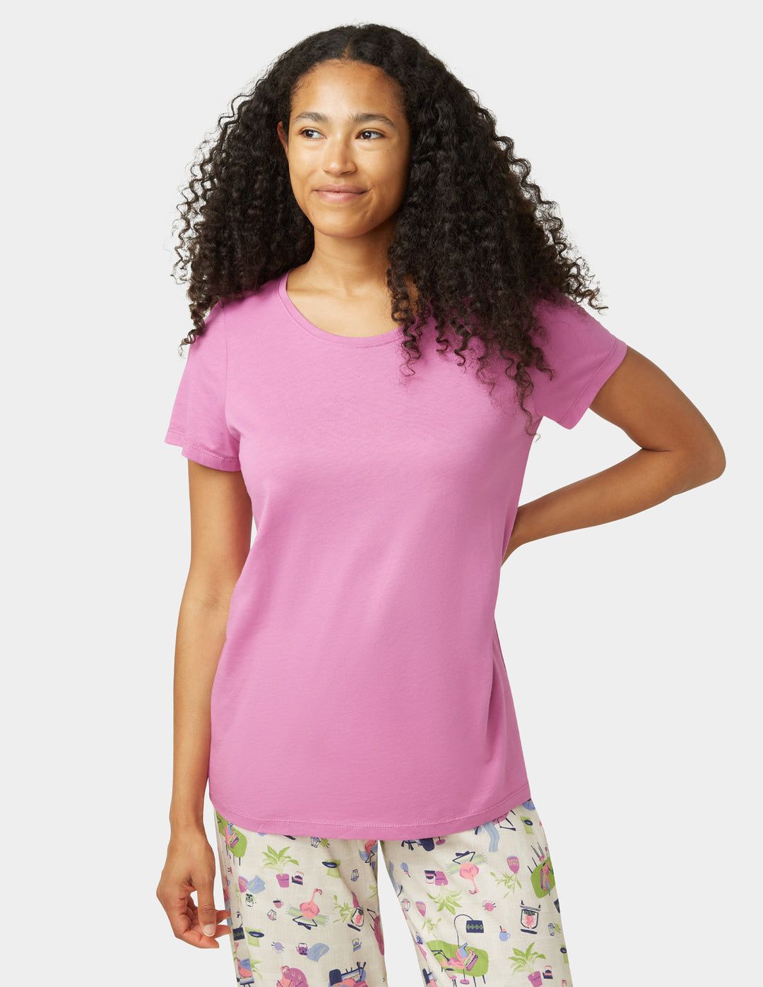 Woman wearing a pink t-shirt and patterned pants on a white background