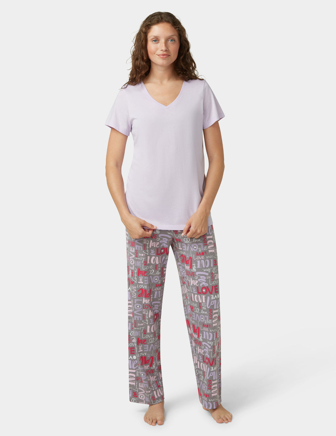 Woman wearing a light purple t-shirt and patterned pants on a white background