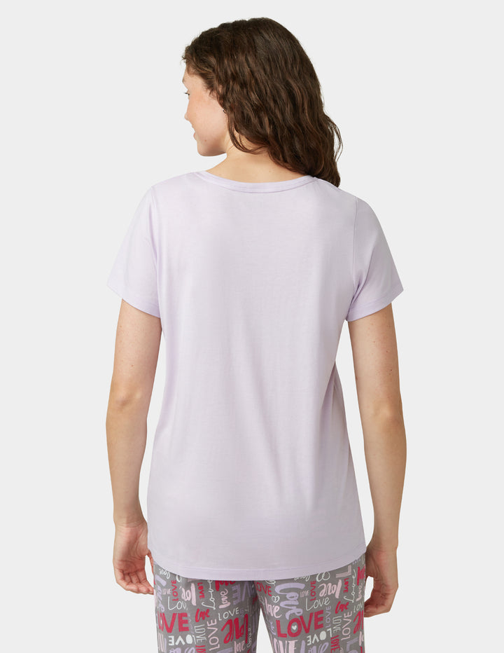 Person wearing a light purple t-shirt and patterned pants on a white background