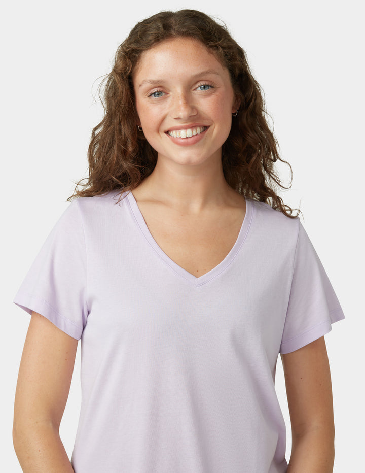 Woman wearing a light purple t-shirt against a plain background