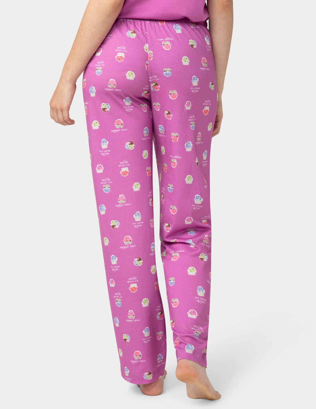 Person wearing pink pajama pants with a pattern on a white background