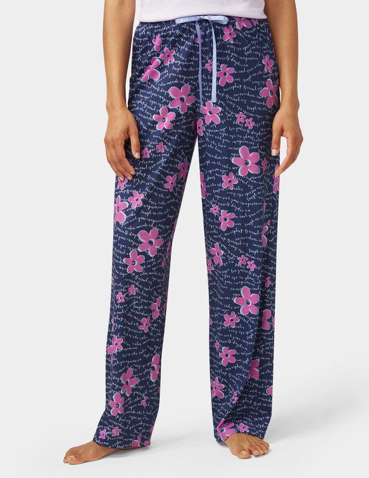 Navy blue pajama pants with pink floral pattern worn by a person on a white background