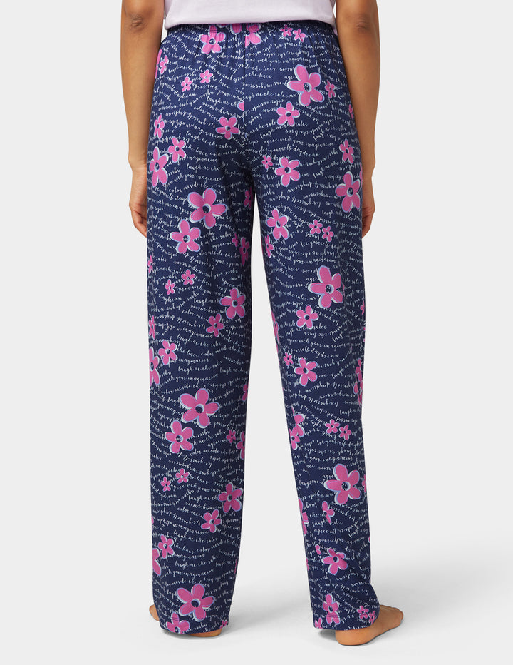 Navy blue pants with pink floral pattern worn by a person on a white background