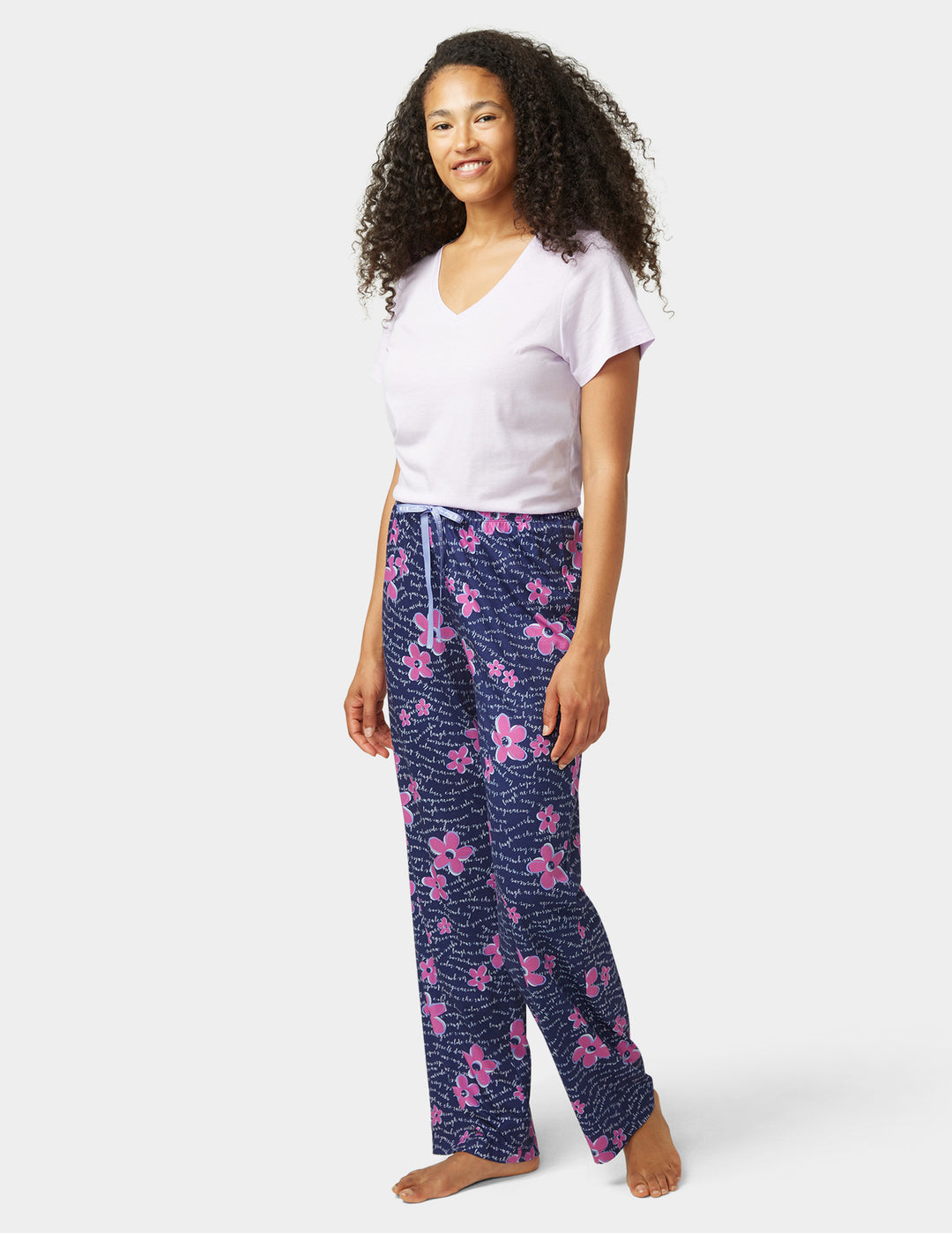 Woman wearing a white t-shirt and blue floral pajama pants on a white background