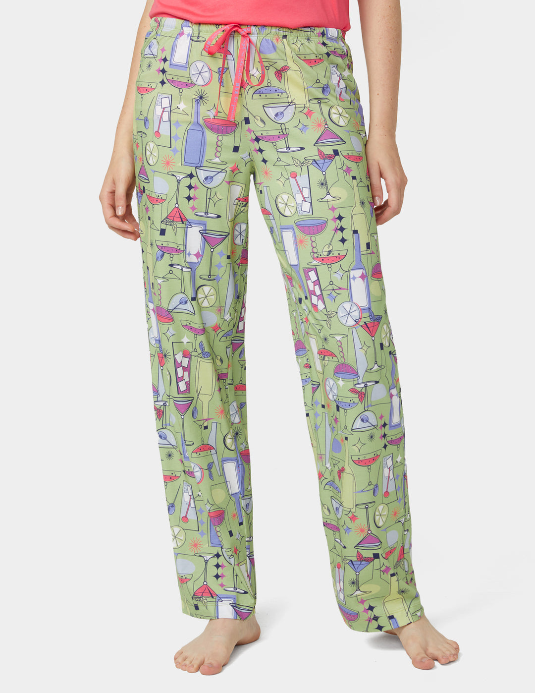 Green pajama pants with colorful cocktail pattern worn by a person on a white background
