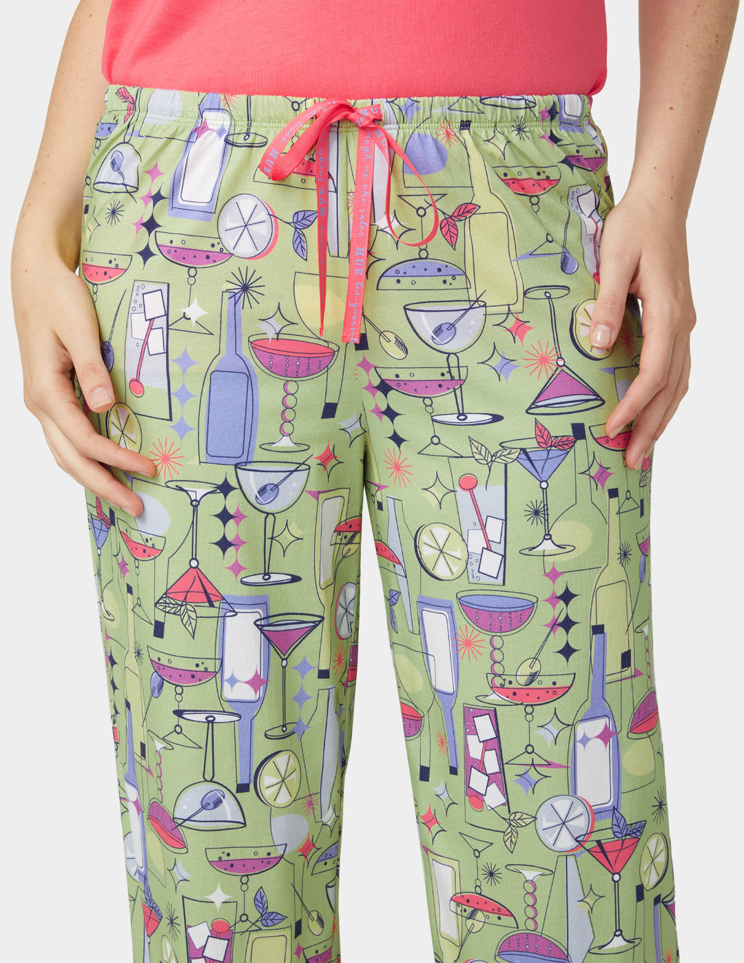 Green pajama pants with cocktail pattern worn by a person, against a white background