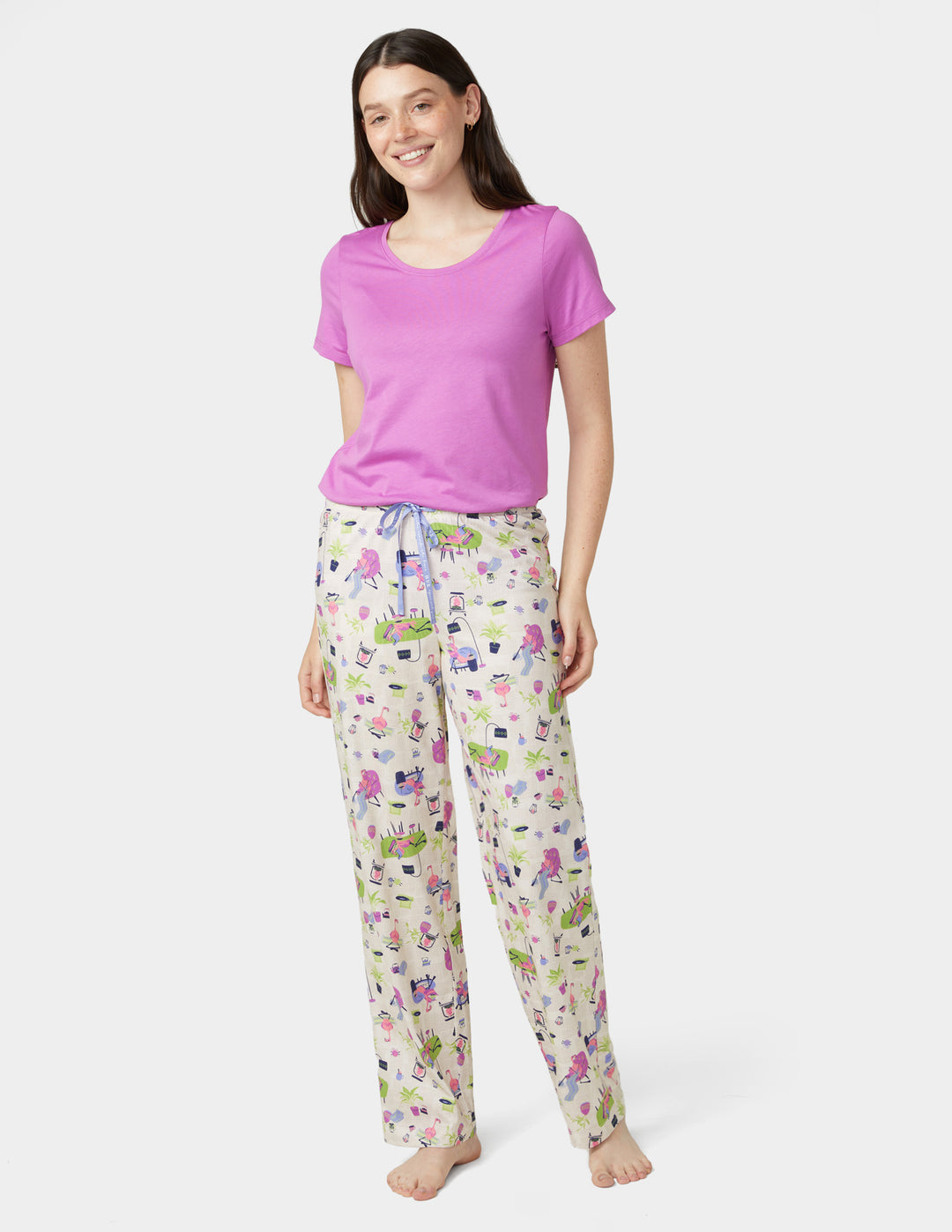 Woman wearing a pink top and floral pajama pants on a white background