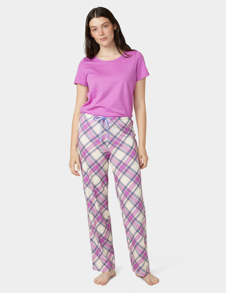Woman wearing a purple t-shirt and plaid pajama pants on a white background